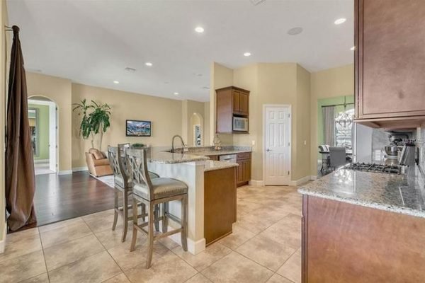 Modern kitchen interior featuring granite countertops, bar stools, and an open layout, part of the 11630 Flynn Ct property in Winter Garden, FL, with spacious living areas and natural light.