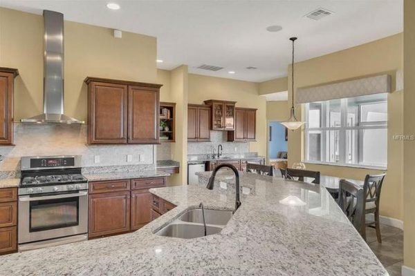Modern kitchen with granite countertops, stainless steel appliances, dark wood cabinetry, and a spacious layout, showcasing the inviting design of the home at 11630 Flynn Ct, Winter Garden, FL.