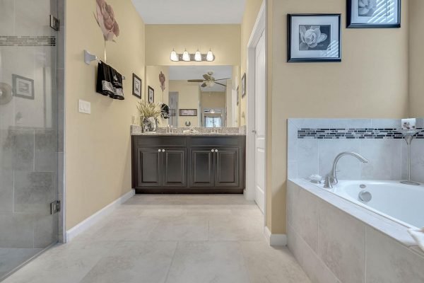 Master bathroom featuring a dark wood vanity with dual sinks, large soaking tub, and glass-enclosed shower, complemented by elegant decor and natural light.