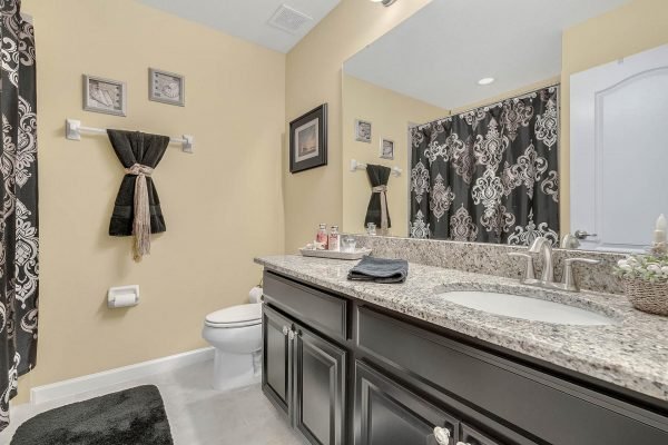 Elegant bathroom featuring granite countertops, black cabinetry, decorative towels, and stylish shower curtain, showcasing modern design elements ideal for the Winter Garden home at 15390 Sandfield Loop.