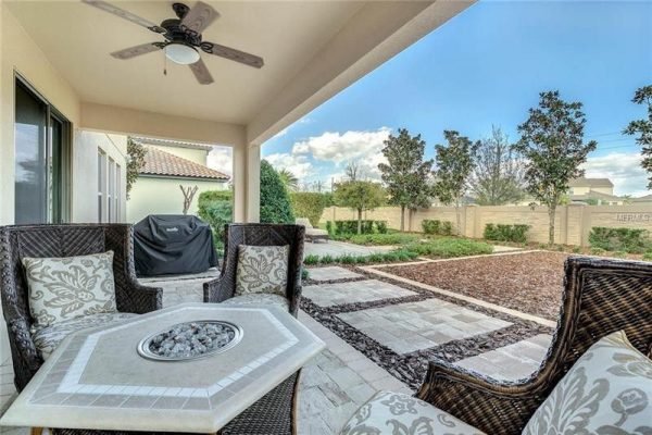 Patio area at 9007 Outlook Rock Trail, Windermere, FL, featuring outdoor seating, a fire pit table, and landscaped backyard with low-maintenance design, ideal for relaxation and entertaining.
