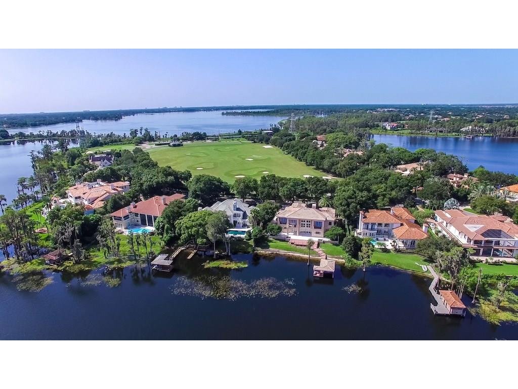Aerial view of luxury homes along a lake in Windermere, Florida, showcasing lush greenery and golf course, relevant to Windermere real estate market insights.