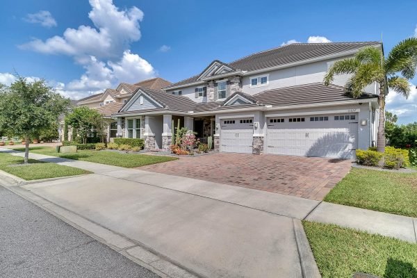 Spacious 5-bedroom home with a three-car garage on Brickyard Pond Lane, Windermere, featuring a landscaped front yard and modern architecture under a blue sky.