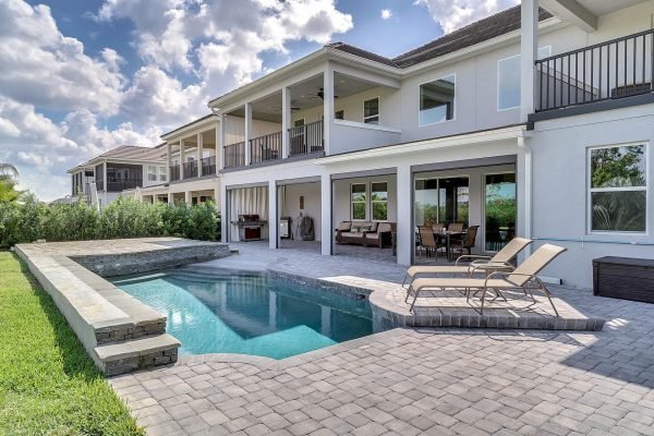 Luxury Windermere lakefront home with private pool, spacious patio, and outdoor seating area, showcasing modern architecture and lush landscaping.