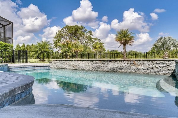 Luxury pool area with stone features and lush landscaping in Windermere, Florida, showcasing a serene outdoor space ideal for relaxation and entertainment.