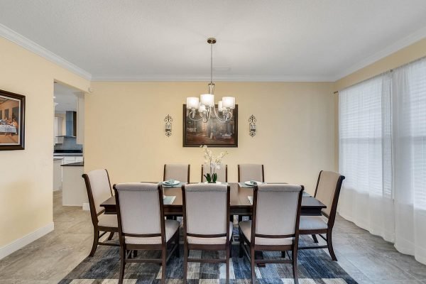 Dining room with a large table and eight chairs, featuring a chandelier and wall art, in a spacious Windermere home.