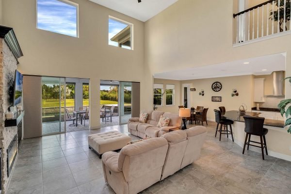 Spacious family room in Windermere estate featuring high ceilings, large windows for natural light, and a view of the backyard pool area.