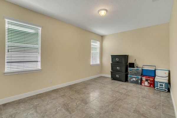 Bonus room in Windermere estate, featuring tile flooring, two windows with blinds, and storage boxes against the wall.