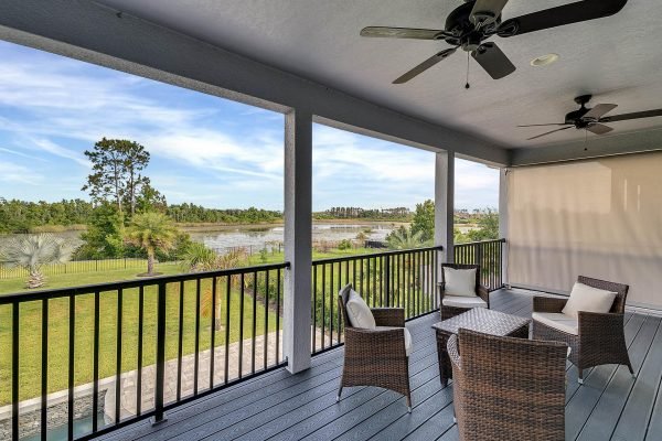 Balcony view of a Windermere lakefront home, featuring outdoor seating and scenic landscape, showcasing lush greenery and water in the background.