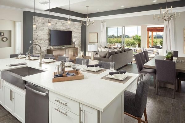 Modern open-concept kitchen and living area with white cabinetry, granite countertops, and stylish dining space, showcasing a comfortable seating arrangement and large windows.