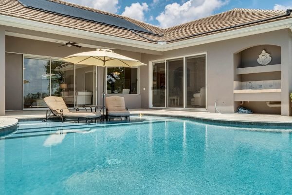 Private lakefront home in Windermere featuring a solar heated infinity pool, patio with umbrella, and views of Lake Roberts.