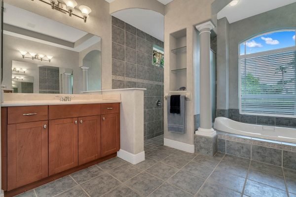 Luxurious bathroom featuring modern fixtures, wooden cabinetry, a soaking tub, and large windows with natural light, complementing the elegant design of the Windermere home at 2039 Water Key Drive.