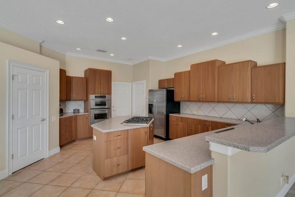 Modern kitchen with wooden cabinetry, granite countertops, and stainless steel appliances in a Windermere lakefront home.