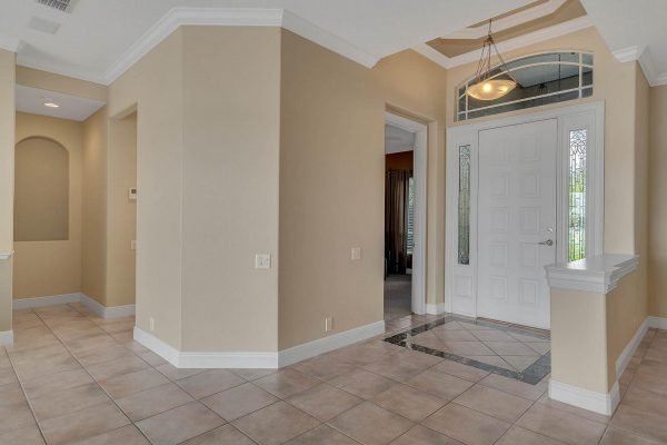 Elegant entryway of a lakefront home in Windermere, featuring tiled flooring, neutral walls, and a decorative front door with glass accents, showcasing an inviting atmosphere for potential buyers.