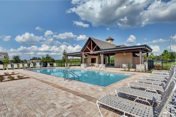 Community pool area with lounge chairs and a covered gazebo in The Preserve at Turtle Creek, Saint Cloud, FL, featuring a clear blue sky and landscaped surroundings.