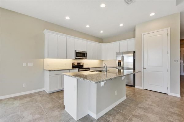 Modern kitchen interior featuring white cabinetry, stainless steel appliances, and granite countertops, designed for the San Andres floor plan at 4756 Riverwalk Dr, Saint Cloud, FL.