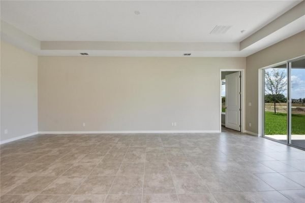 Spacious interior of a new construction home at 4756 Riverwalk Dr, Saint Cloud, FL, featuring tiled flooring and large windows, showcasing natural light and views of the outdoor area.