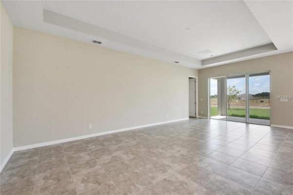 Spacious living room in new home at 4756 Riverwalk Dr, Saint Cloud, FL, featuring tile flooring, large windows, and natural light.