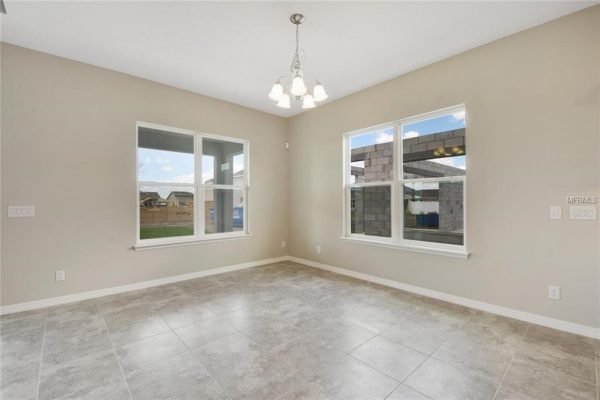 Interior view of a new home at 4756 Riverwalk Dr, Saint Cloud, FL, featuring large windows, tiled flooring, and modern light fixtures, highlighting the spacious layout of the San Andres floor plan.