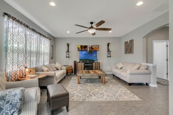Cozy family room in a home at 2989 Park Meadow Drive, featuring plush seating, decorative wall art, a large TV, and natural light from window treatments, showcasing modern design elements and a welcoming atmosphere.