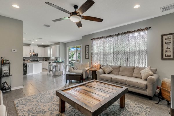 Modern family room with a cozy couch, wooden coffee table, and large windows, showcasing a bright and inviting space in a home for sale in Apopka, FL.