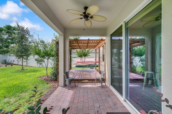 Lanai area of 2989 Park Meadow Drive, Apopka, FL featuring a pergola, brick paver flooring, and seating overlooking a private backyard with lush greenery.
