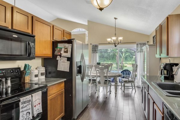 Modern kitchen with stainless steel appliances, wooden cabinets, and a view of the outdoor patio and pond area, emphasizing the home's inviting atmosphere near 633 Remington Oak Dr, Lake Mary, FL.