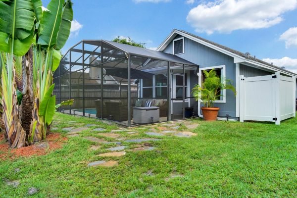 Backyard of 633 Remington Oak Dr, Lake Mary, FL, featuring a screened pool area surrounded by lush greenery, including palm trees, and a well-maintained lawn, emphasizing privacy and tranquility near conservation area.