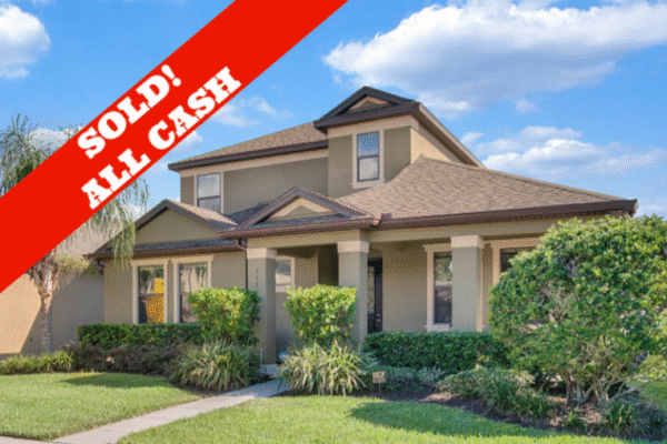 Sold sign on a Windermere home with a well-maintained exterior, lush landscaping, and blue sky background, indicating recent sale for cash.