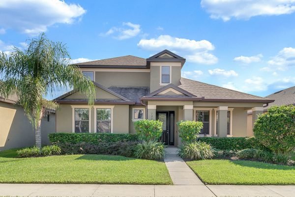 Meticulously maintained single-family home at 13318 Longacre Dr, Windermere, featuring a covered porch, lush landscaping, and a fully fenced yard, ideal for family living.
