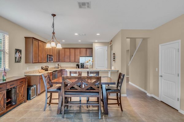 Dining area featuring a wooden table with chairs, modern kitchen with dark wood cabinets, granite countertops, and stainless steel appliances in a meticulously cared for Windermere home.