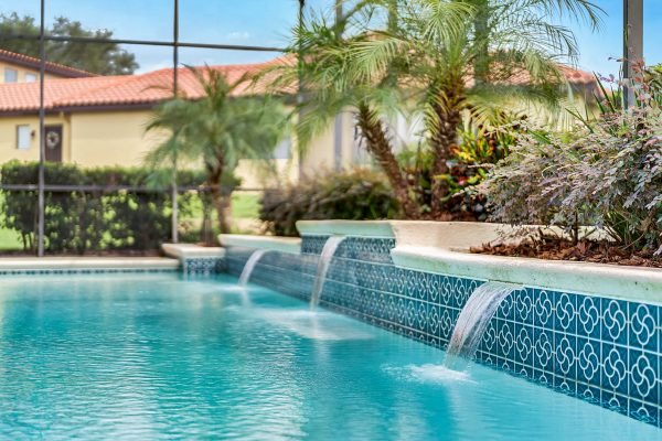 Luxury pool with water features, surrounded by tropical landscaping and screened enclosure, at 17744 Deer Isle Cir, Winter Garden, FL.
