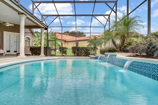 Inground pool with water features, surrounded by screened lanai and tropical landscaping, showcasing outdoor living space of luxury home at 17744 Deer Isle Cir, Winter Garden, FL.