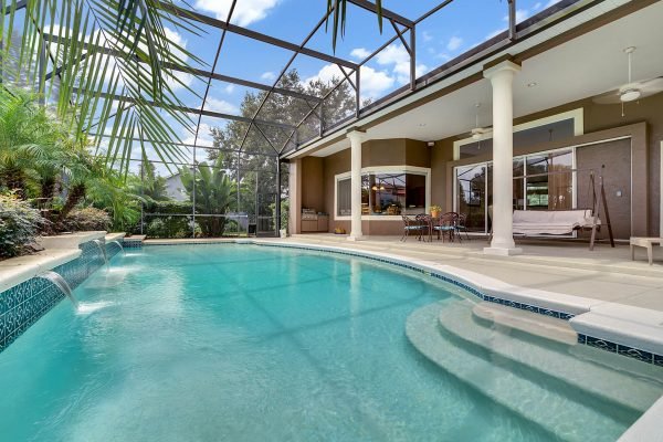 Inground pool with screened enclosure, tropical landscaping, and patio area at 17744 Deer Isle Cir, Winter Garden, FL, showcasing outdoor living space in a luxury home setting.
