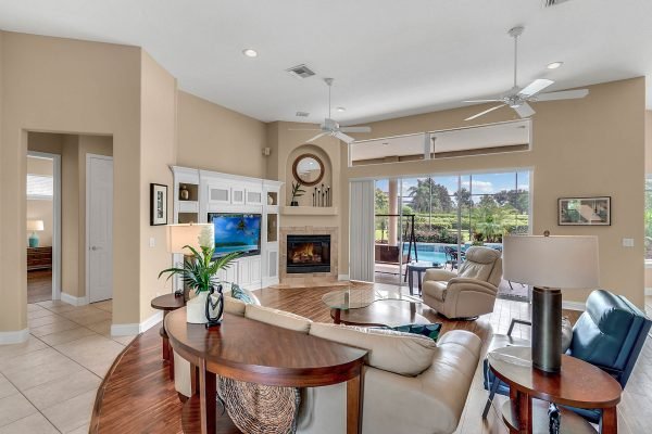 Spacious family room with elegant furnishings, large windows overlooking the pool, fireplace, and custom built-ins, showcasing the luxurious interior of the home at 17744 Deer Isle Cir, Winter Garden, FL.