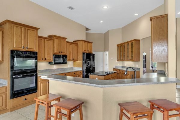 Spacious kitchen with custom wood cabinetry, modern appliances, and a large island, featuring a breakfast bar and open layout, ideal for entertaining in a luxury home at 17744 Deer Isle Cir, Winter Garden, FL.