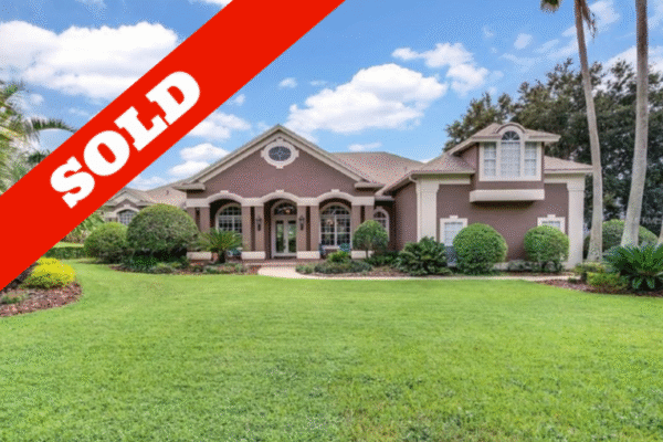 Sold home in Winter Garden, Florida, featuring a landscaped front yard with lush greenery and palm trees, showcasing a spacious single-story residence with a distinctive architectural design.