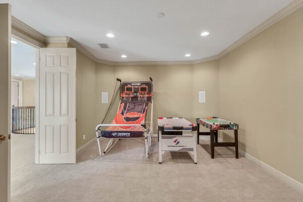 Bonus room featuring a basketball game and air hockey table, showcasing recreational space in a luxury home at 1837 Lake Roberts Landing Dr, Winter Garden, FL.