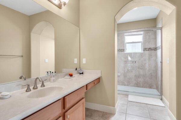 Spacious bathroom featuring dual sinks, light-colored cabinetry, and a walk-in shower with glass enclosure, highlighting modern design elements in the luxury home at 1837 Lake Roberts Landing Dr, Winter Garden, FL.