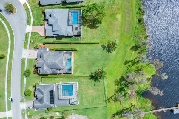 Aerial view of luxury homes with swimming pools along Lake Roberts, showcasing expansive green lawns and proximity to water, highlighting the desirable lakefront property features in Winter Garden, FL.