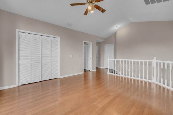 Upstairs loft area with wooden flooring, ceiling fan, and white railings, showcasing the spacious layout of the home at 12847 Sharp Shined Street, Orlando, FL.