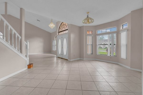 Spacious entryway of 12847 Sharp Shined Street, Orlando, featuring large double doors, high ceilings, and tile flooring, showcasing bright natural light and an open layout.