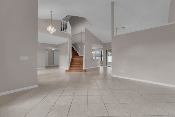 Spacious interior of 12847 Sharp Shined Street in Orlando, featuring a two-story layout, tile flooring, staircase, and large windows allowing natural light.