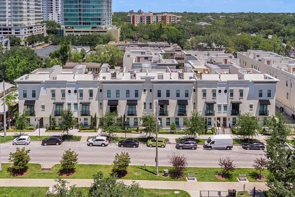 Modern brownstone residences on E Jackson St, Orlando, featuring three-story facades, lush landscaping, and secure parking, situated near parks and downtown amenities.