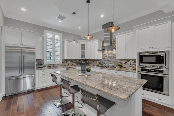 Modern kitchen featuring granite countertops, stainless steel appliances, white cabinetry, and pendant lighting, designed for entertaining in a luxury brownstone setting near downtown Orlando.