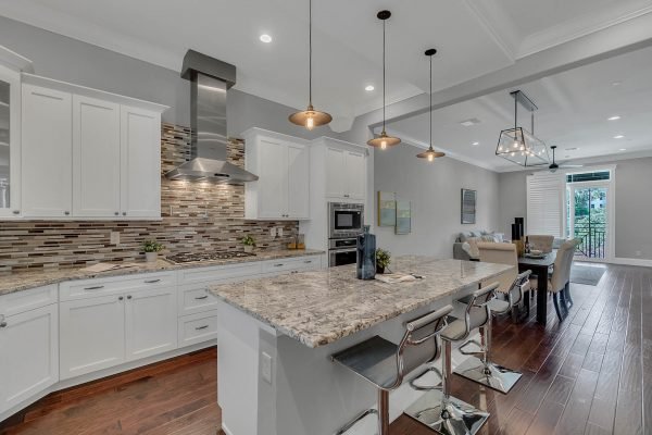 Modern kitchen with granite countertops, stainless steel appliances, and stylish pendant lighting, featuring an open layout connected to a dining area, showcasing a contemporary design ideal for entertaining in downtown Orlando.