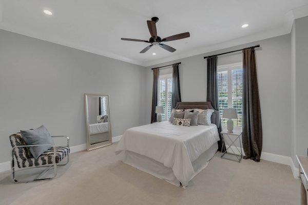 Spacious bedroom in luxurious brownstone with neutral decor, large windows, stylish bedding, and modern furnishings, showcasing an inviting atmosphere for downtown living near Orlando's amenities.