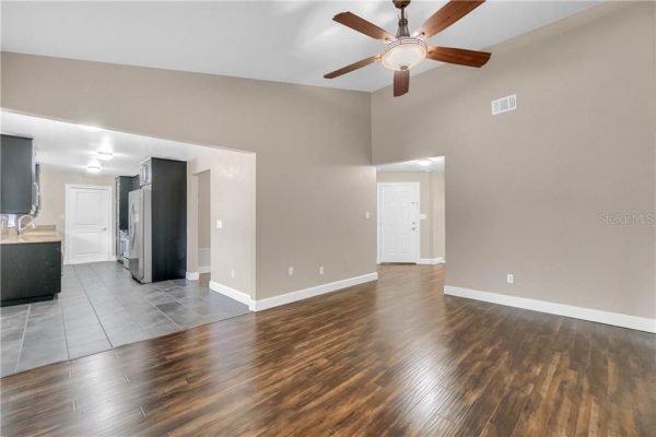 Interior view of a modern living space featuring hardwood flooring, ceiling fan, and open layout connecting to a kitchen area, suitable for showcasing a remodeled home in Windermere, FL.