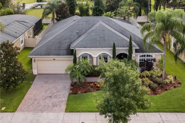 Single-story home at 12703 Dallington Terrace in Winter Garden, FL, featuring a landscaped front yard, paver driveway, and palm trees, ideal for family living.