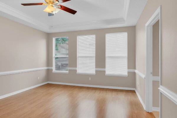 Spacious interior of a Windermere home featuring hardwood floors, crown molding, and large windows with blinds, ideal for natural light and a welcoming atmosphere.